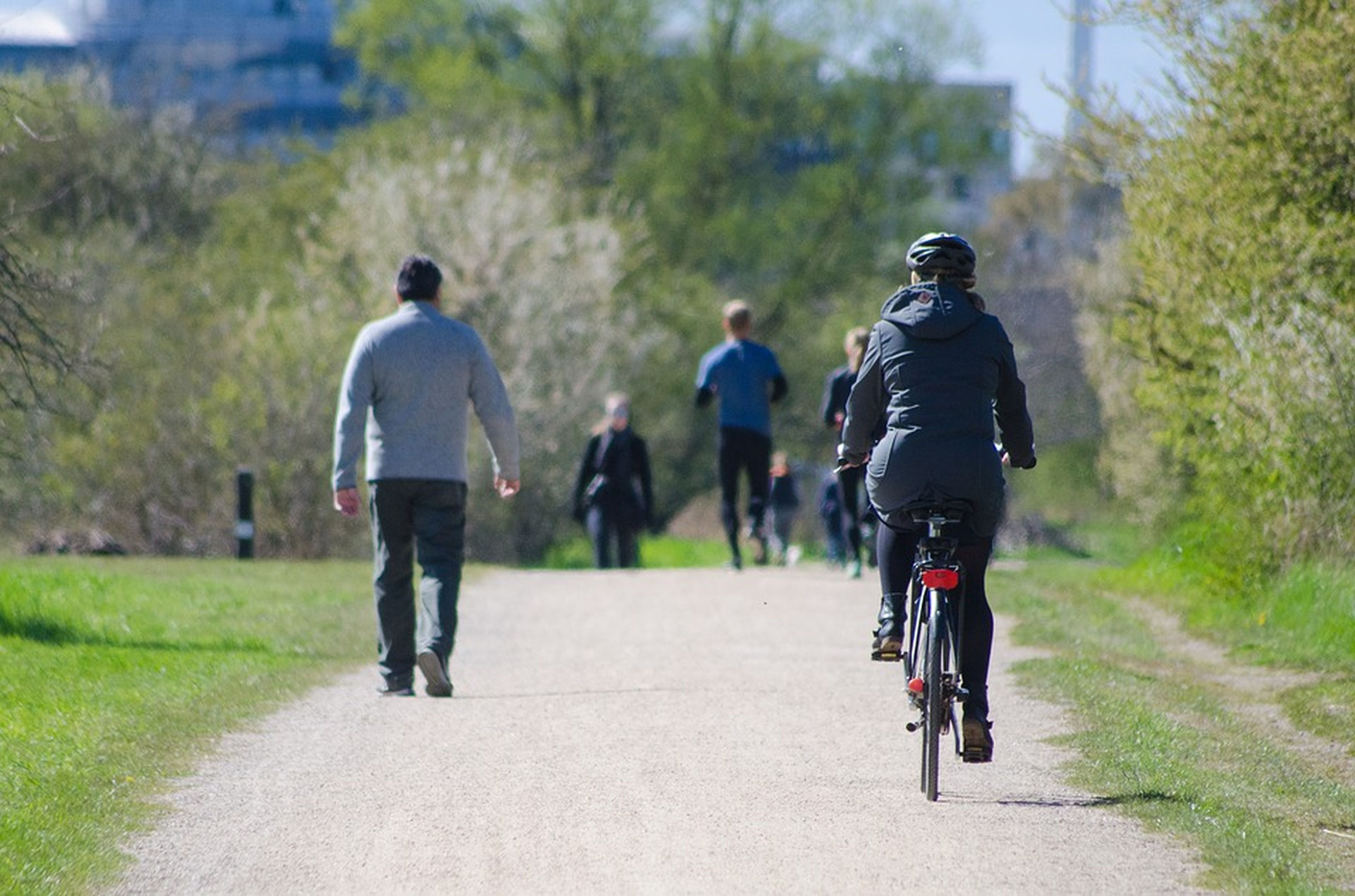 Un grupo de gente y una mujer en bicicleta en una vía verde