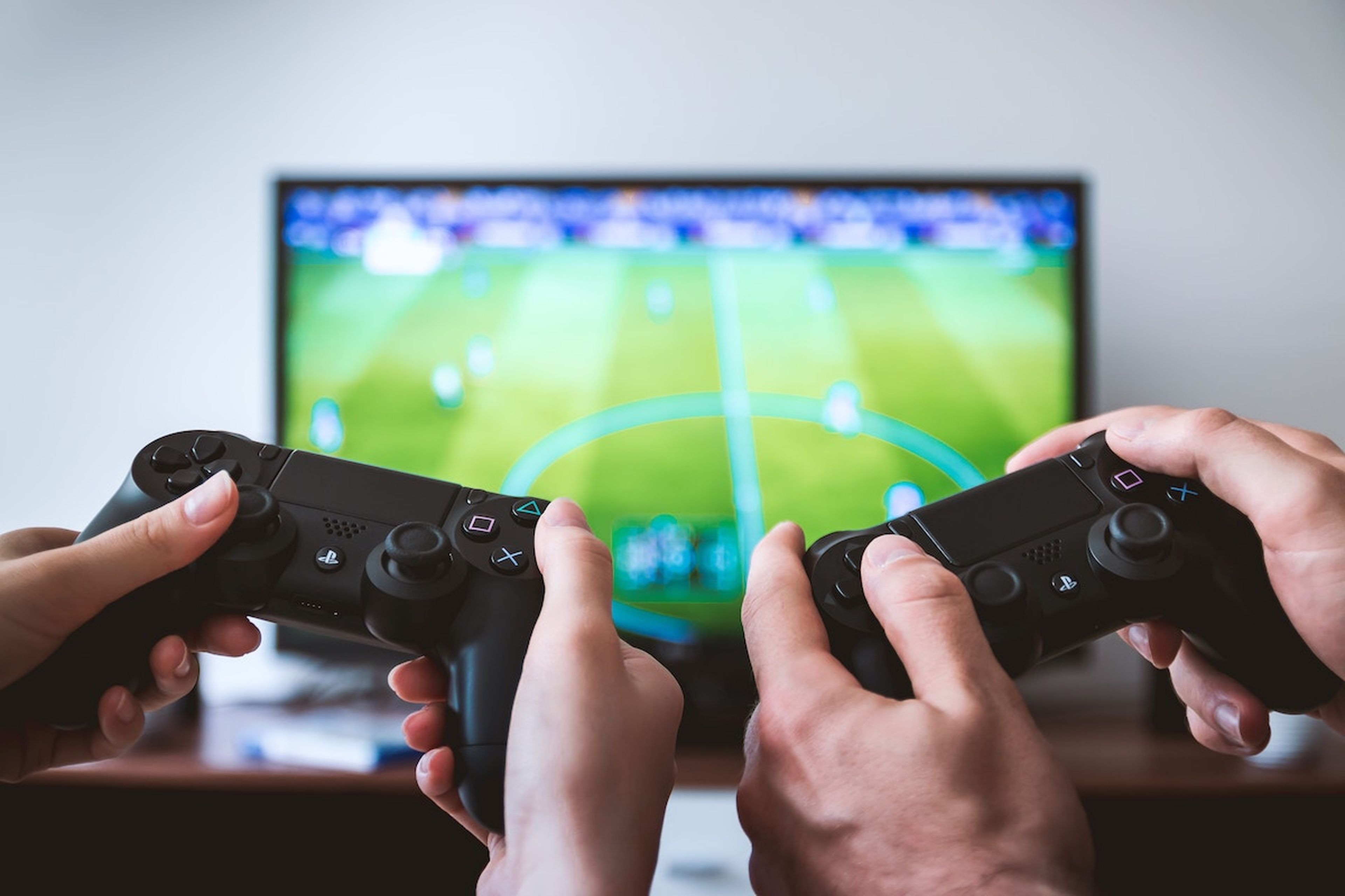 Dos personas con mandos de PS4 jugando a FIFA