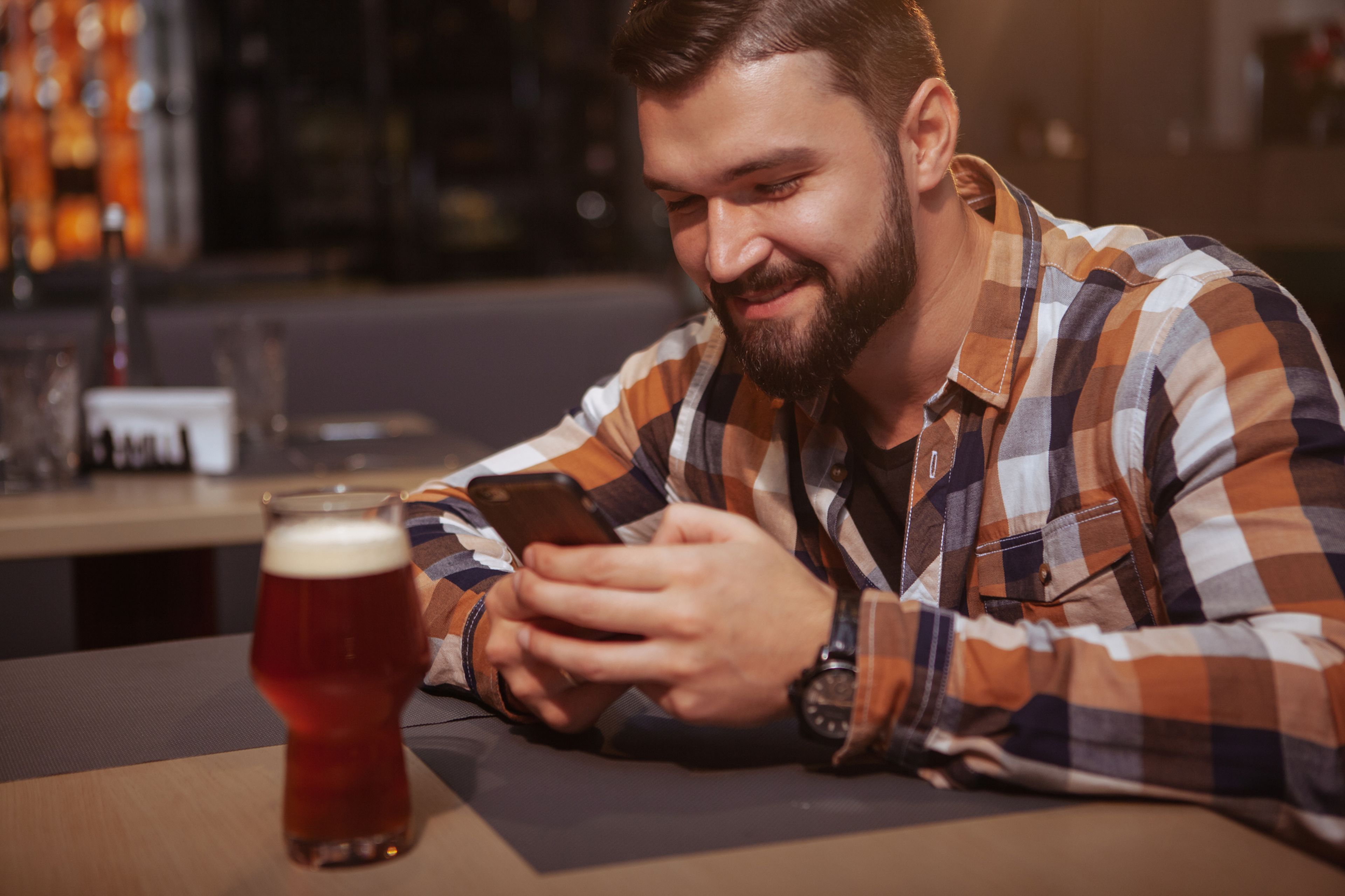 Hombre usando móvil y bebiendo cerveza