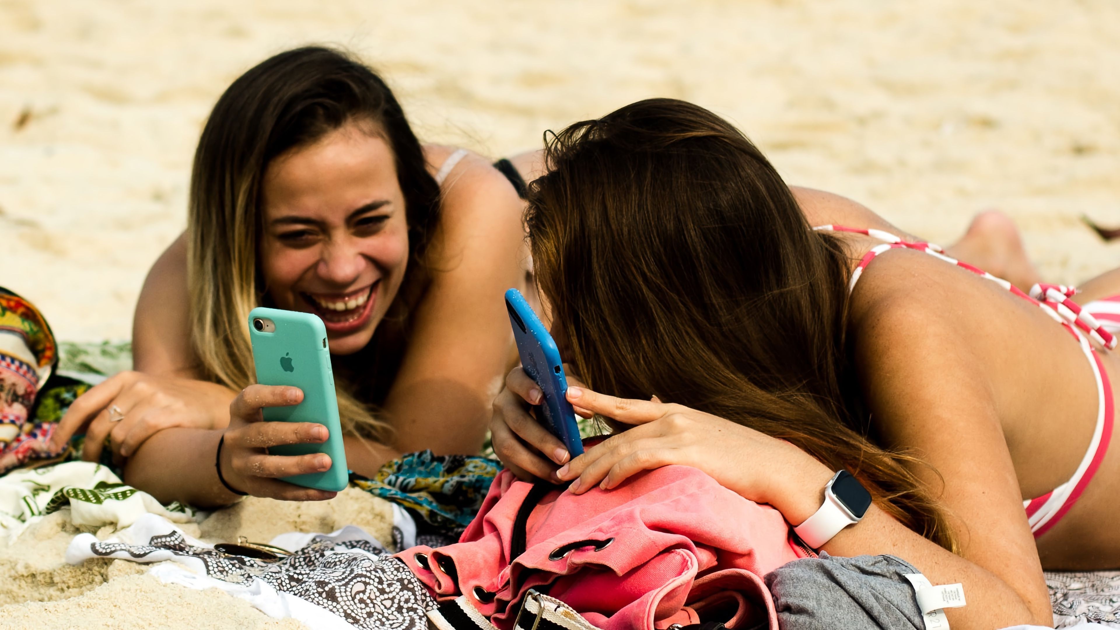 Chicas jóvenes con móviles en la playa