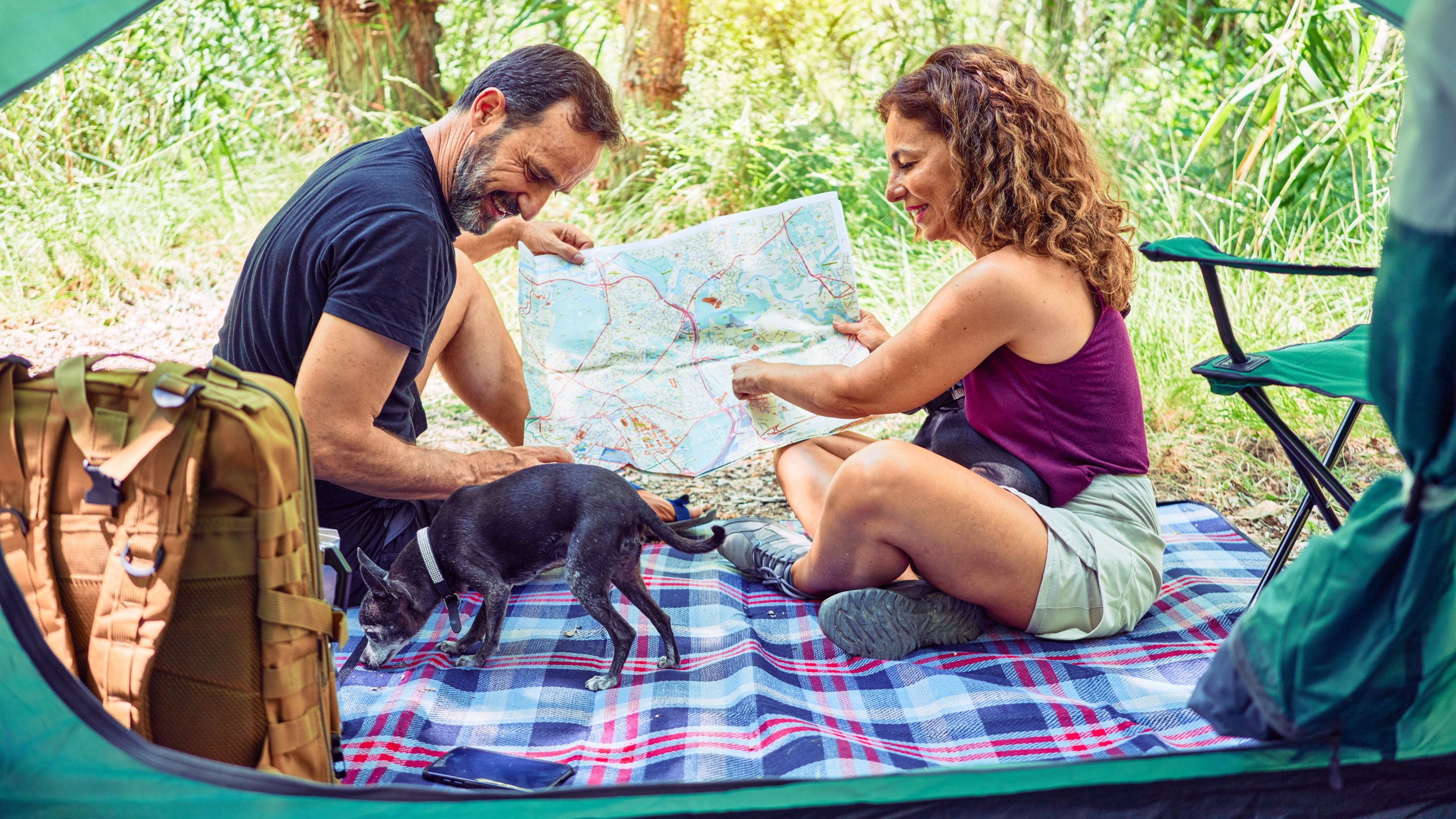 Pareja y perro de vacaciones mirando un mapa