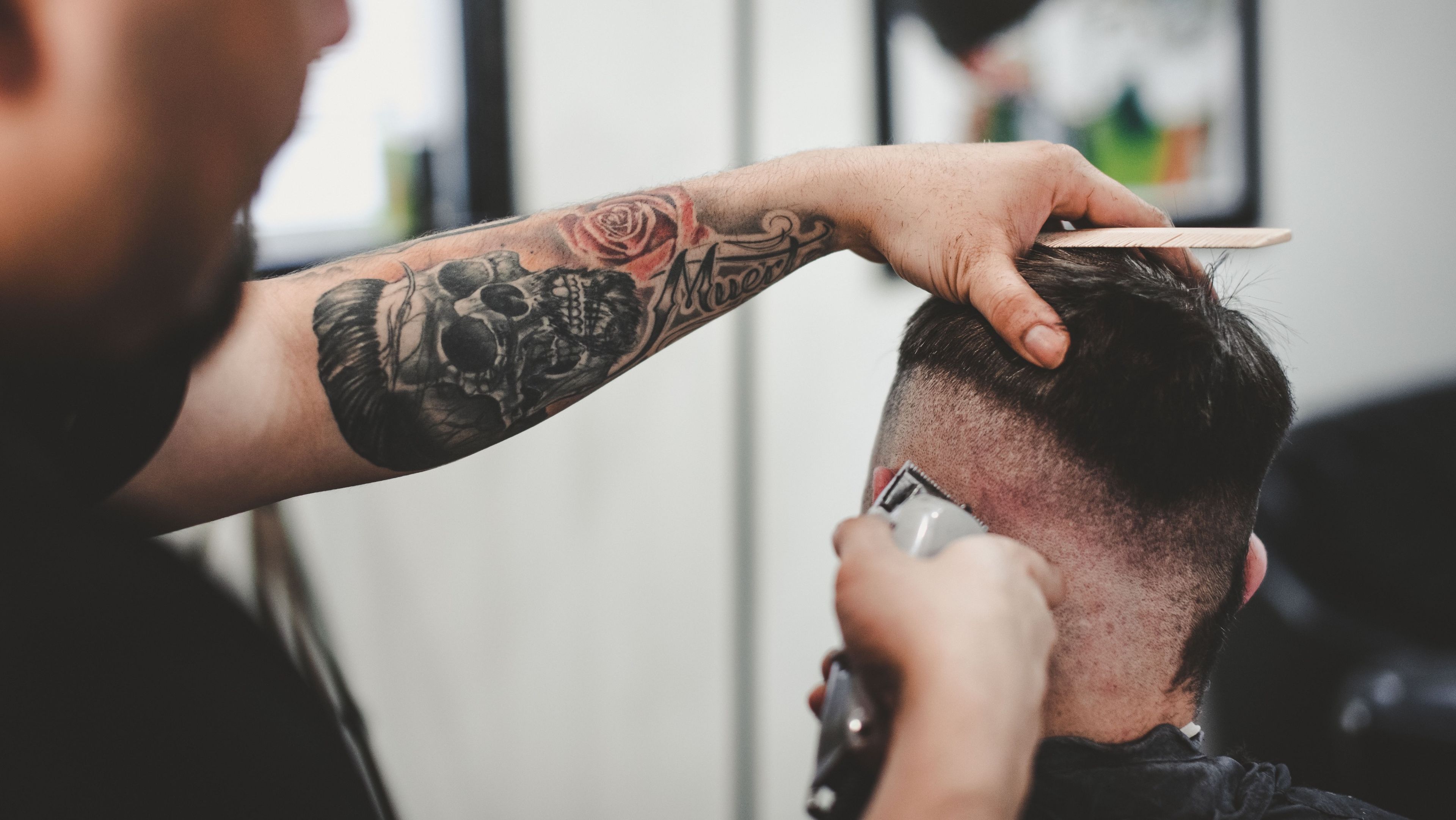 Hombre cortando el pelo a otro hombre con un cortapelos