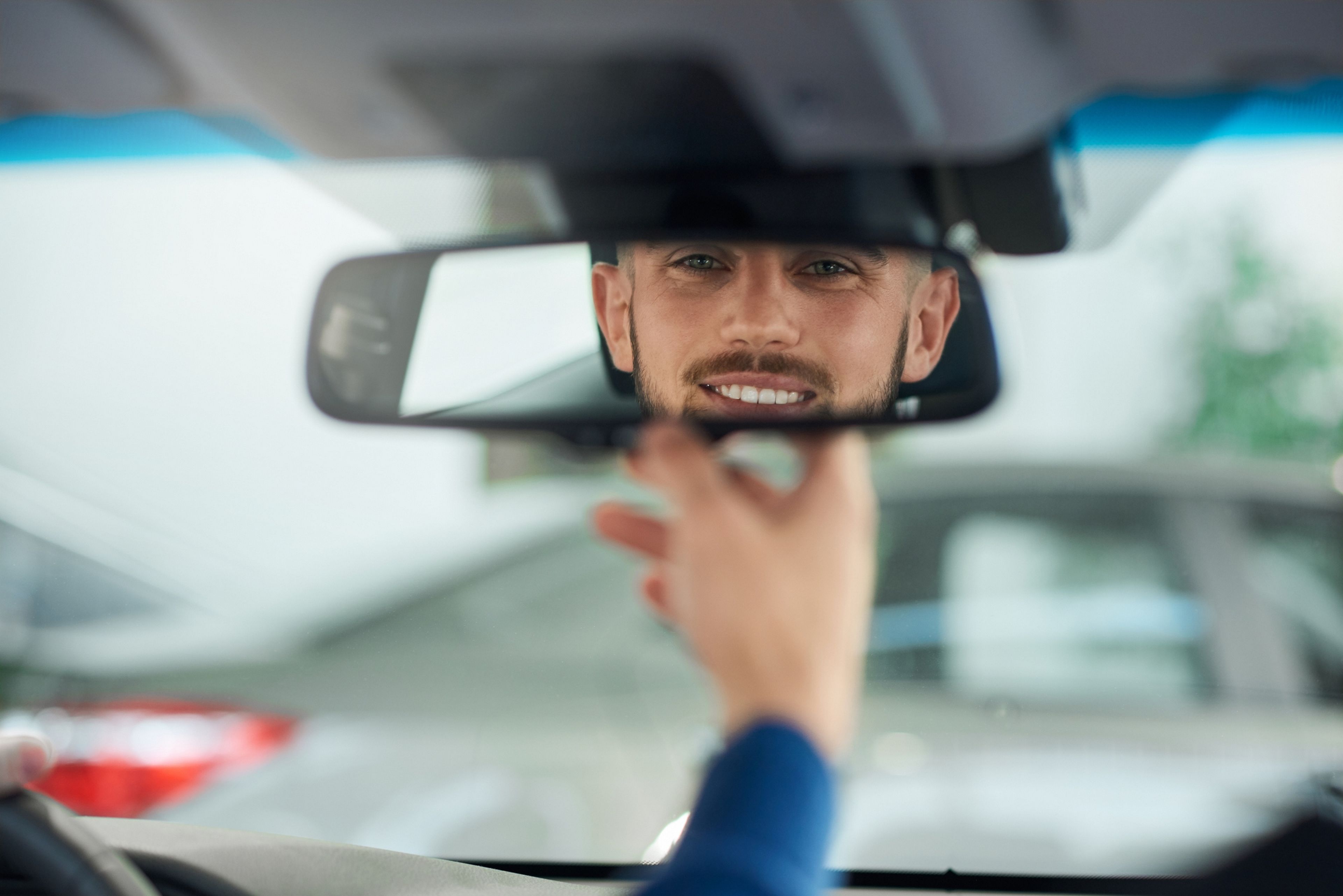 Водитель смотрит в зеркало. В зеркале машины мужчина.