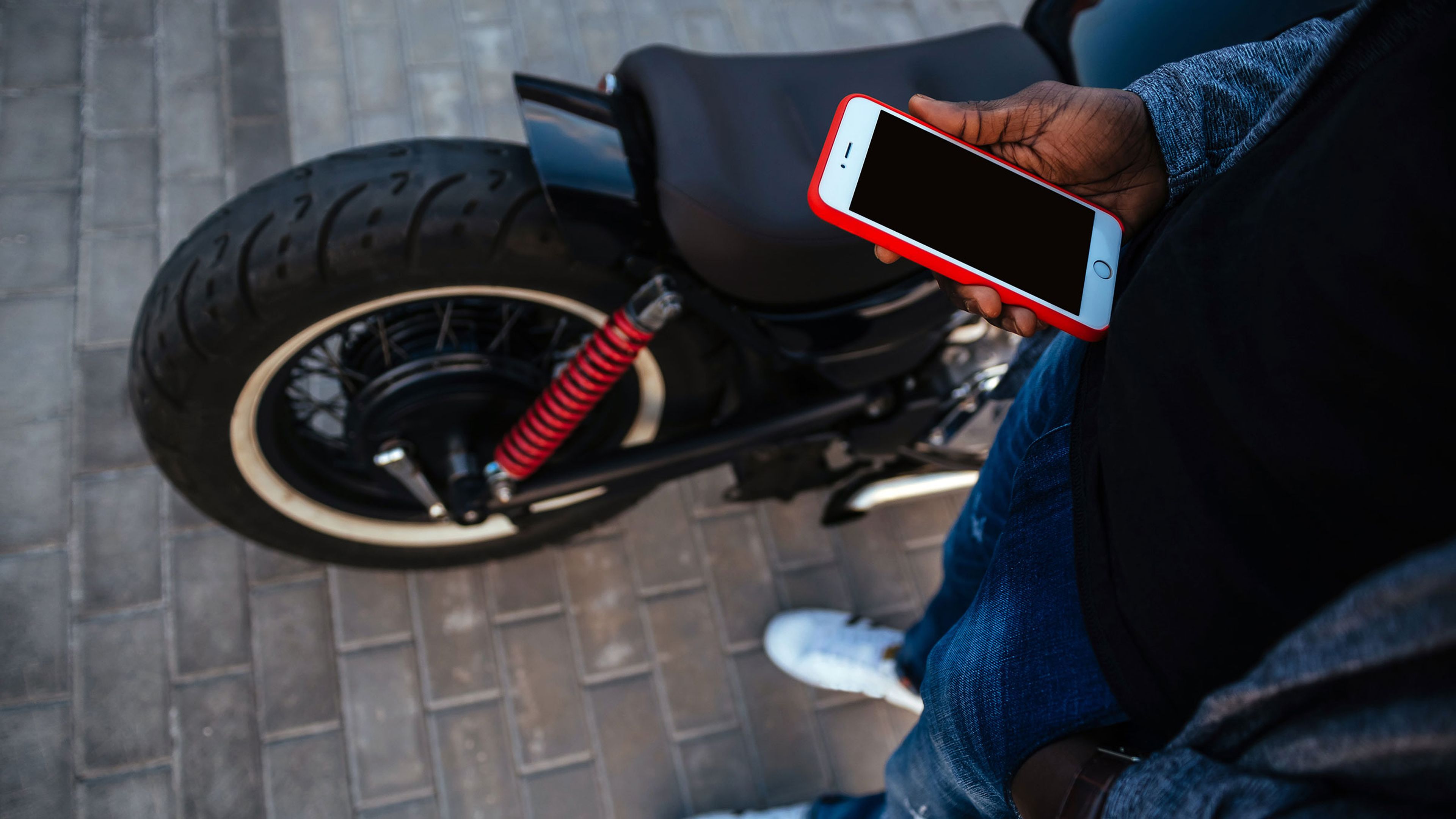 Hombre sostiene un iPhone junto a una moto