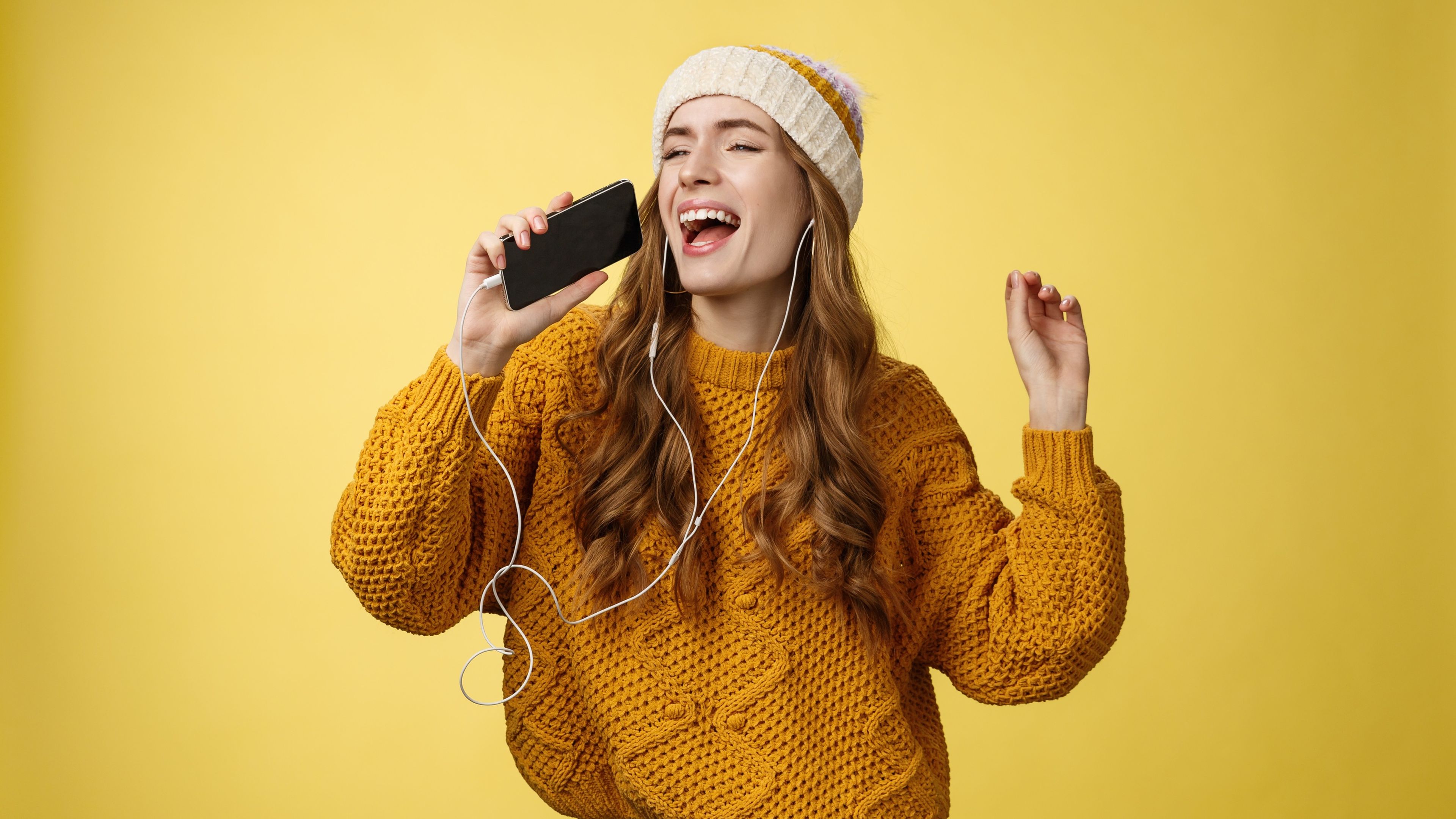 Mujer escuchando música con unos auriculares con cable y un iPhone