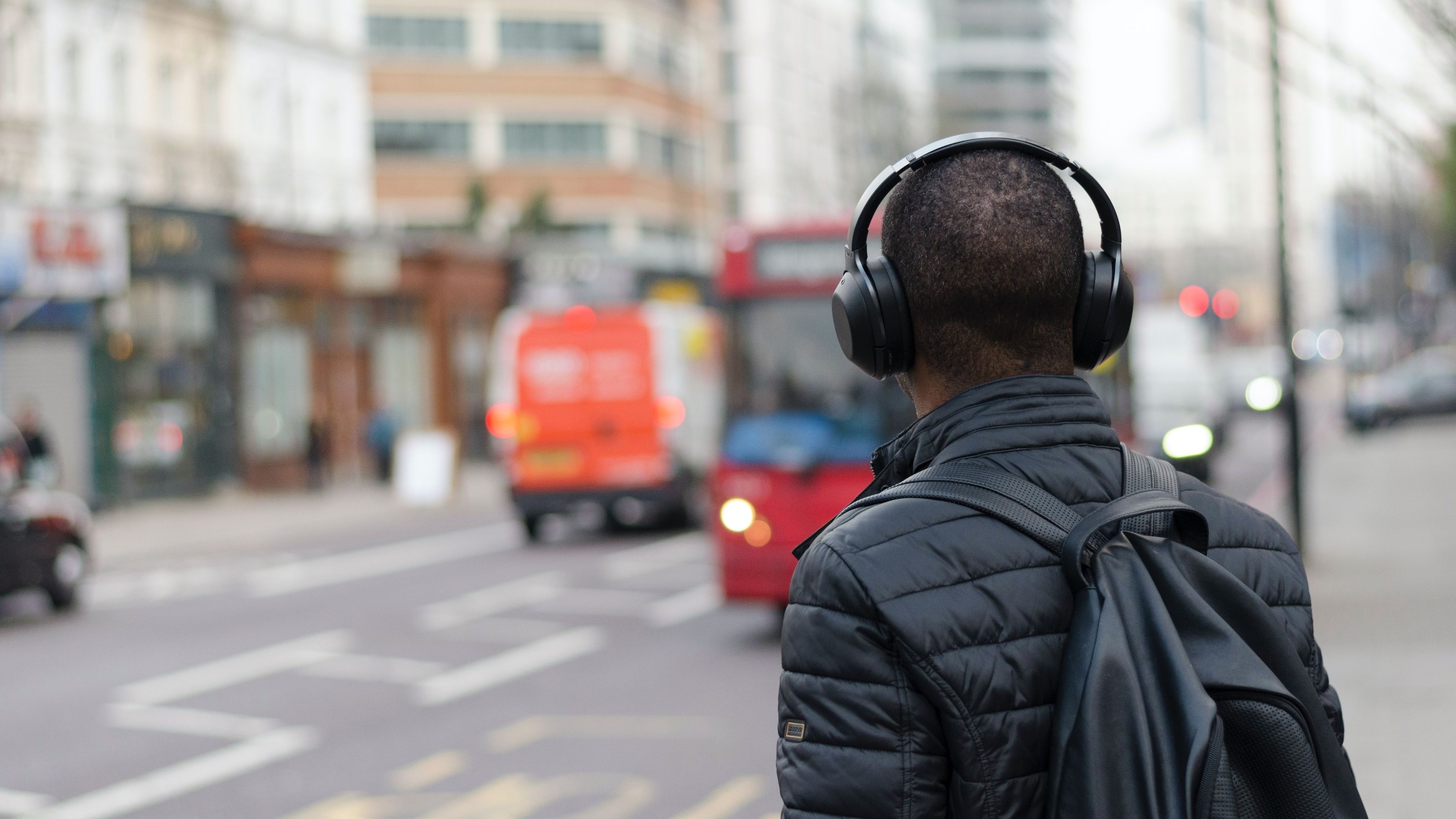 Hombre escuchando música con auriculares en una calle concurrida