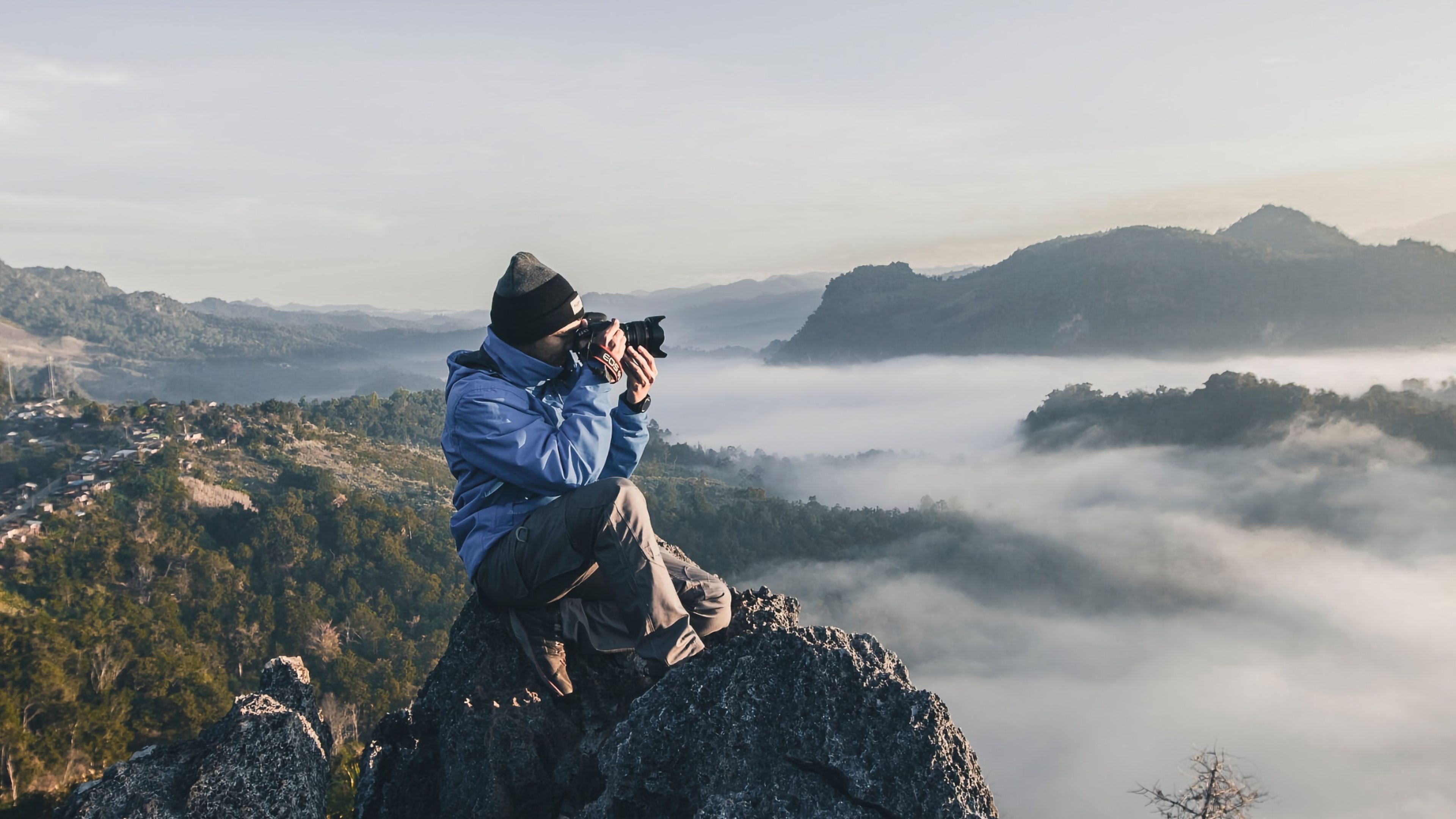 Persona en lo alto de una montaña tomando una fotografía con una cámara Canon