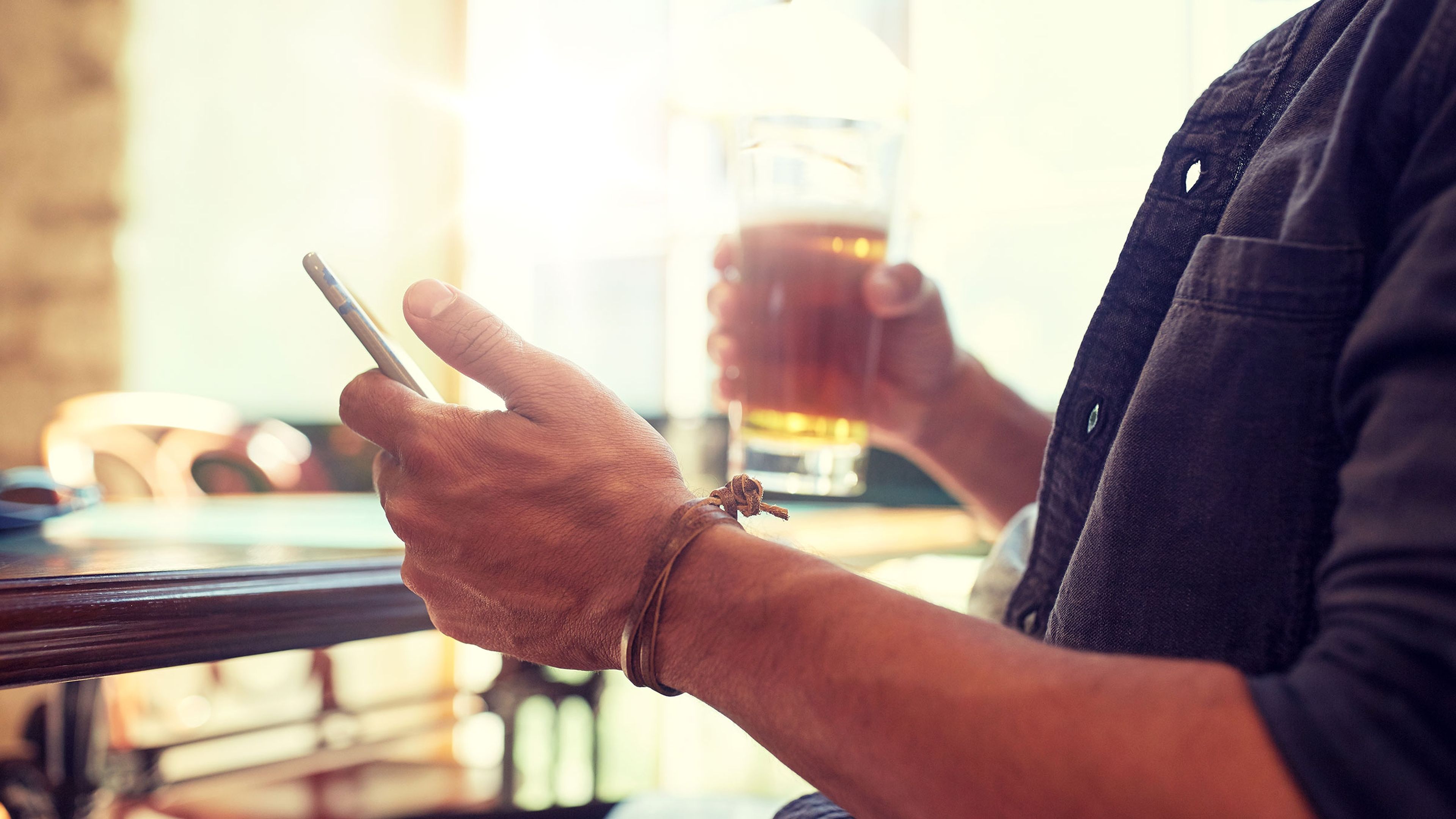 Persona usando un móvil y bebiendo cerveza