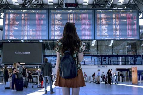 Joven en el aeropuerto buscando vuelos Joven en el aeropuerto buscando vuelos