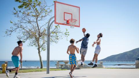 Cuatro hombres jugando una partida de baloncesto en una cancha al aire libre